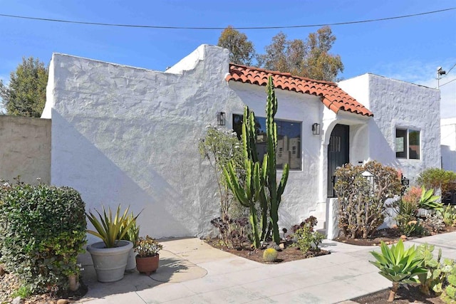 exterior space with a tiled roof and stucco siding