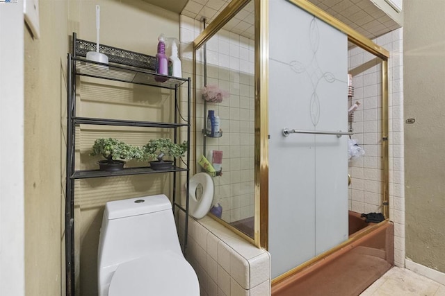 bathroom featuring tile patterned floors, toilet, and combined bath / shower with glass door