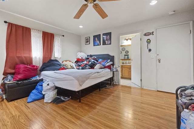 bedroom with wood-type flooring, ensuite bathroom, and ceiling fan