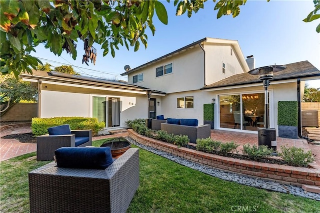 back of property with a yard, outdoor lounge area, a patio, and solar panels