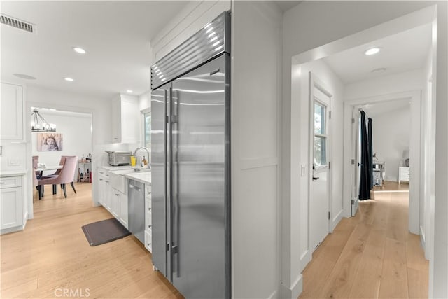 hallway featuring an inviting chandelier, sink, and light hardwood / wood-style floors