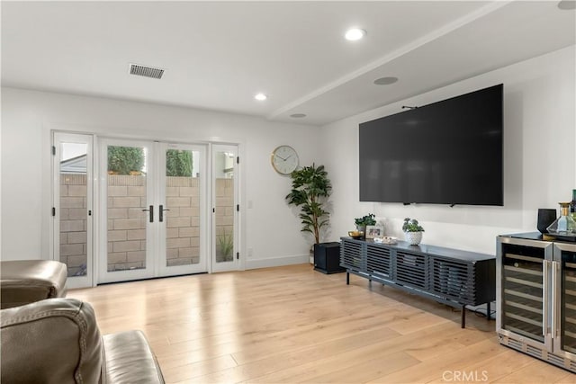 living room with french doors, beverage cooler, and light hardwood / wood-style floors