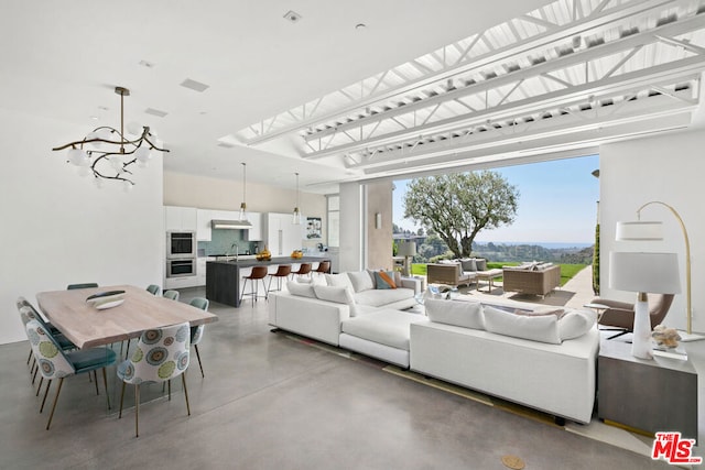 living room with an inviting chandelier, sink, a skylight, and concrete flooring