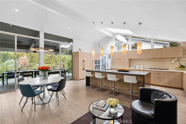 kitchen with hanging light fixtures, a kitchen island, light brown cabinetry, and light hardwood / wood-style flooring