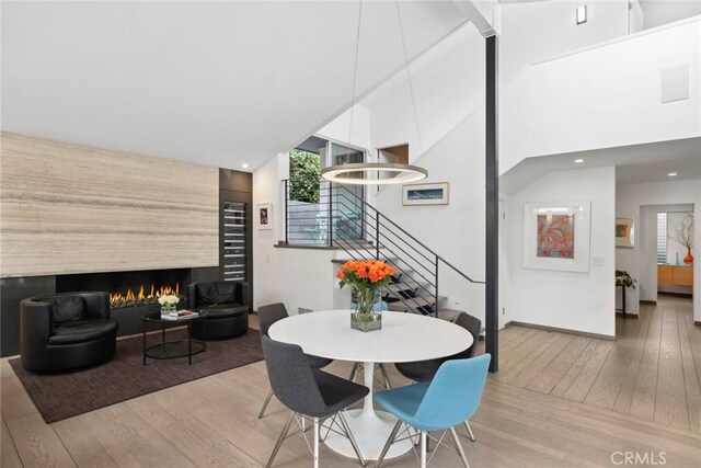 1900 Catalina St, Laguna Beach, CA 92651 - dining room with a lit fireplace, recessed lighting, a high ceiling, stairs, and wood-type flooring