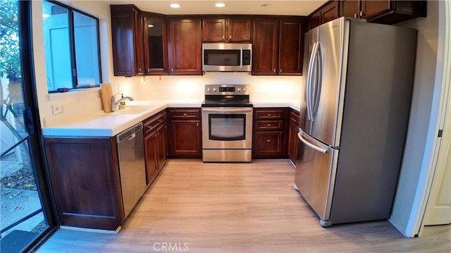 kitchen with stainless steel appliances, light hardwood / wood-style floors, and sink