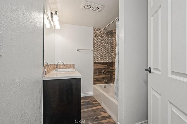 bathroom with vanity, tiled shower / bath combo, and hardwood / wood-style floors