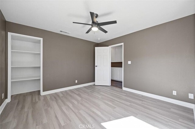 unfurnished bedroom featuring ceiling fan, light hardwood / wood-style floors, and a closet