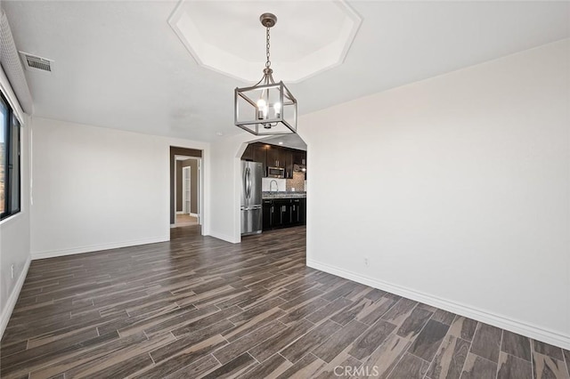 interior space with sink, a tray ceiling, dark wood-type flooring, and a chandelier