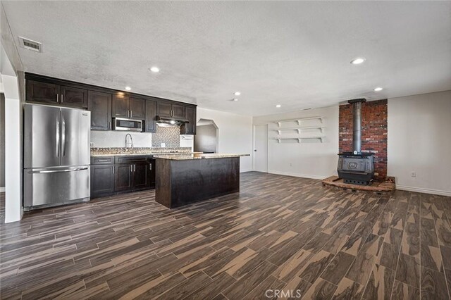 kitchen with dark hardwood / wood-style flooring, backsplash, stainless steel appliances, and a center island