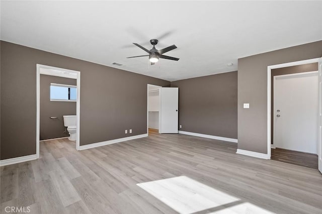 interior space featuring a walk in closet, connected bathroom, light hardwood / wood-style floors, and a closet