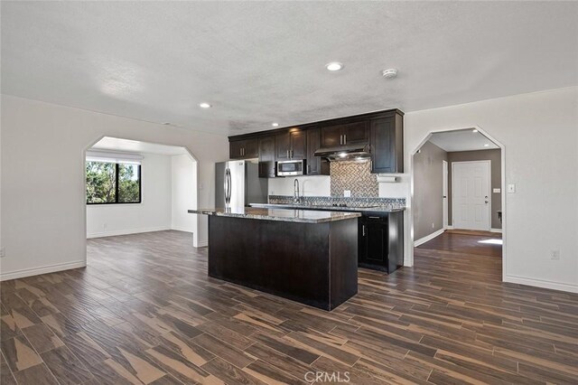 kitchen featuring decorative backsplash, dark hardwood / wood-style floors, stainless steel appliances, and a center island