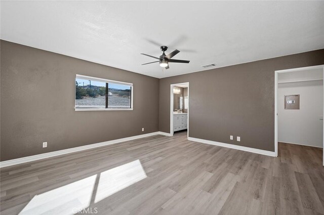 unfurnished bedroom with ceiling fan, ensuite bath, and light wood-type flooring