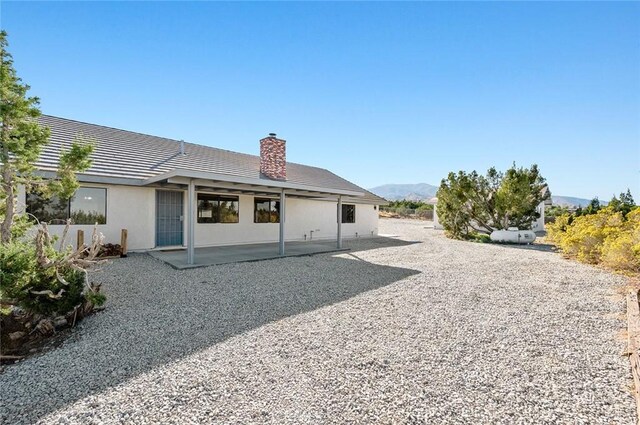 back of property with a mountain view and a patio area