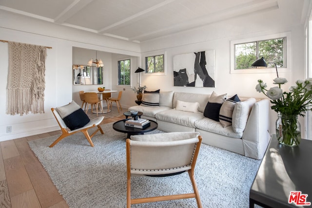 living room featuring beam ceiling, hardwood / wood-style flooring, and an inviting chandelier