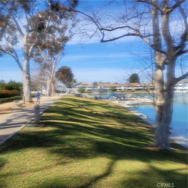 view of community with a dock, a yard, and a water view