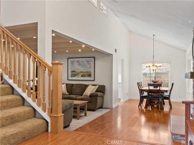 interior space featuring a notable chandelier, high vaulted ceiling, wood finished floors, stairway, and baseboards