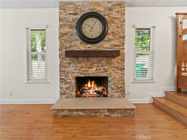 unfurnished living room with a stone fireplace, a healthy amount of sunlight, and wood finished floors