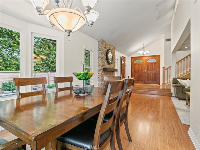 dining room with light wood-style floors, an inviting chandelier, and vaulted ceiling