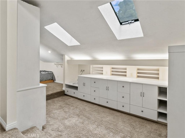 interior space featuring vaulted ceiling with skylight and baseboards