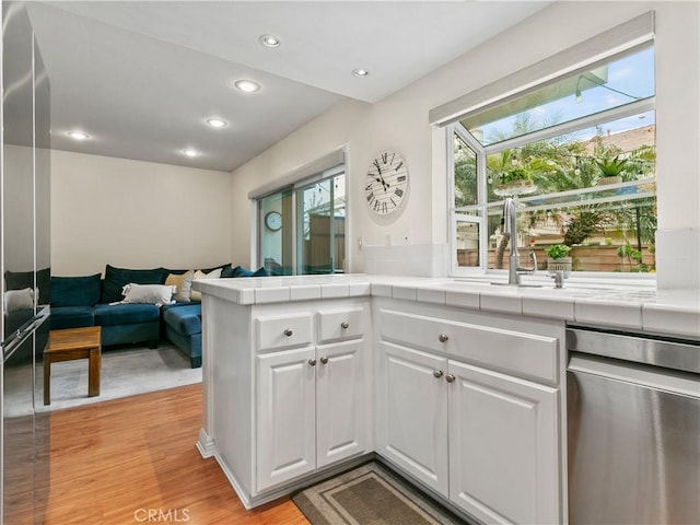 kitchen with dishwasher, tile counters, white cabinets, and a healthy amount of sunlight