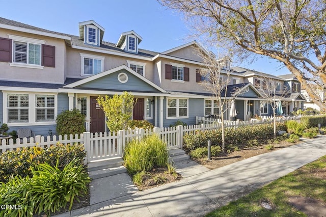 townhome / multi-family property with a fenced front yard and stucco siding