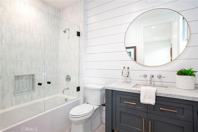 full bathroom with vanity, wooden walls, toilet, and tiled shower / bath