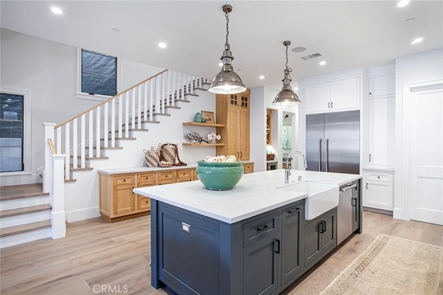 kitchen with sink, gray cabinetry, hanging light fixtures, a kitchen island with sink, and stainless steel appliances