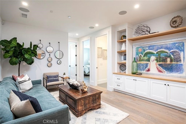 living room featuring built in shelves and light hardwood / wood-style flooring