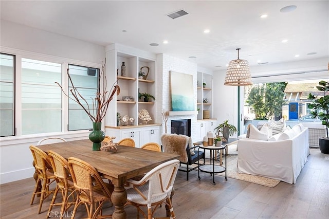 dining space with hardwood / wood-style flooring, a fireplace, and built in features