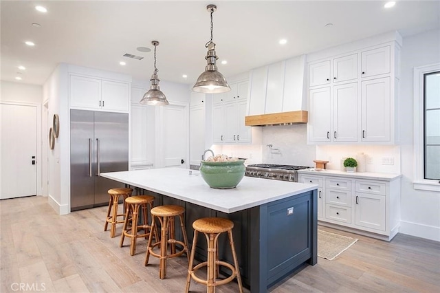 409 39th St, Newport Beach, CA 92663 - kitchen with stainless steel appliances, an island with sink, white cabinetry, light wood-type flooring, and recessed lighting