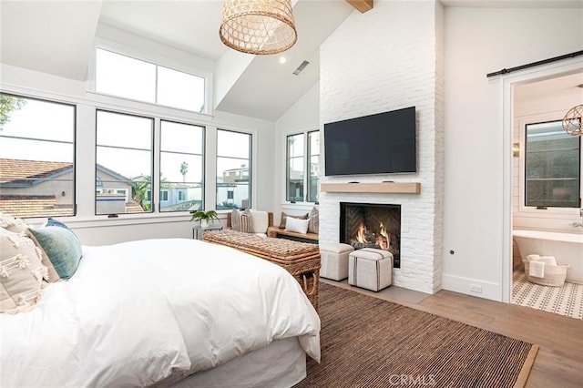 409 39th St, Newport Beach, CA 92663 - bedroom featuring wood finished floors, a large fireplace, high vaulted ceiling, a barn door, and ensuite bath