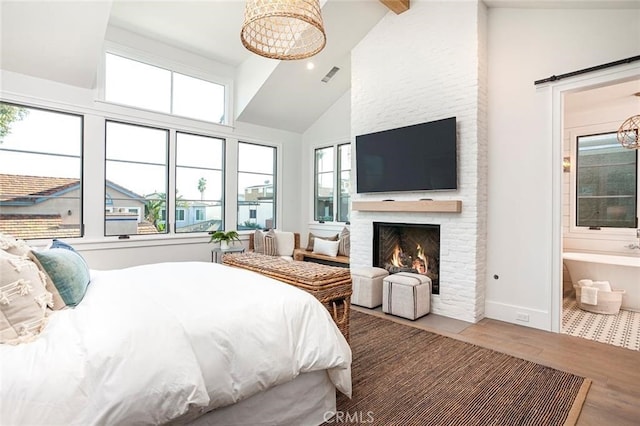 409 39th St, Newport Beach, CA 92663 - bedroom featuring wood finished floors, high vaulted ceiling, a fireplace, a barn door, and connected bathroom