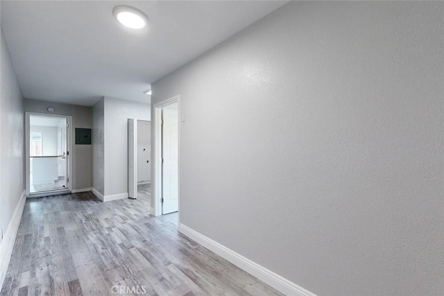 hallway featuring electric panel and light hardwood / wood-style floors