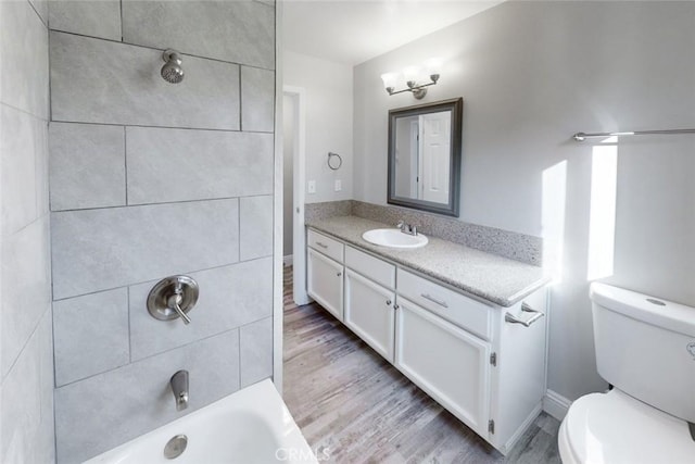 full bathroom with tiled shower / bath, wood-type flooring, toilet, and vanity