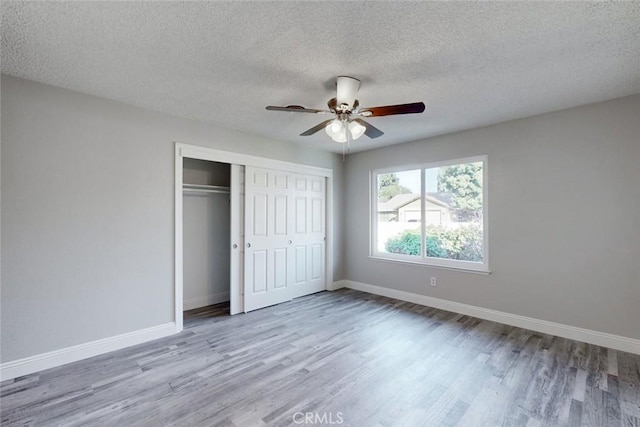 unfurnished bedroom with a closet, a textured ceiling, ceiling fan, and light hardwood / wood-style flooring