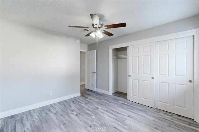 unfurnished bedroom featuring a closet, ceiling fan, a textured ceiling, and light hardwood / wood-style flooring