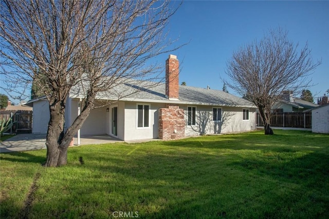 back of house featuring a patio area and a lawn