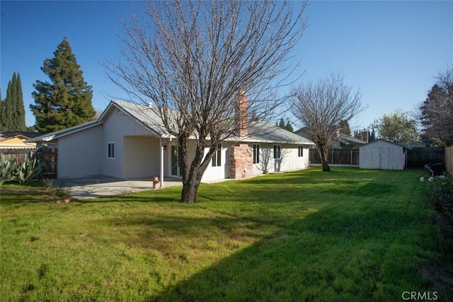 rear view of property featuring a shed, a yard, and a patio