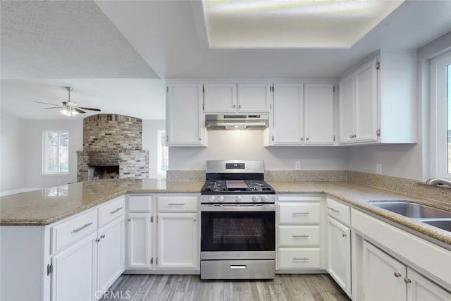 kitchen with white cabinets, sink, stainless steel gas range, and kitchen peninsula