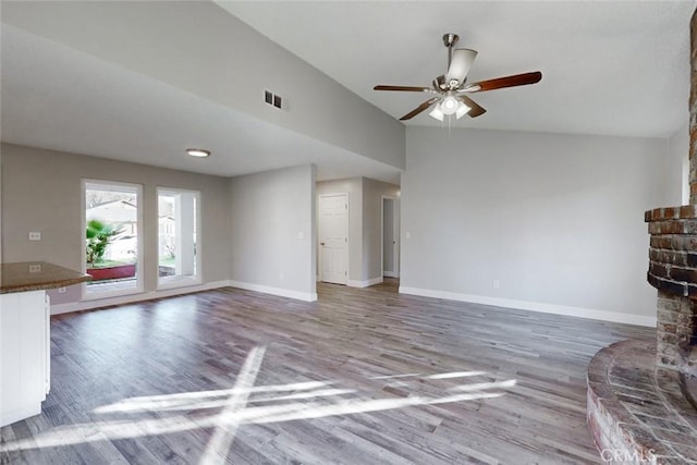 unfurnished living room with vaulted ceiling, hardwood / wood-style floors, a fireplace, and ceiling fan