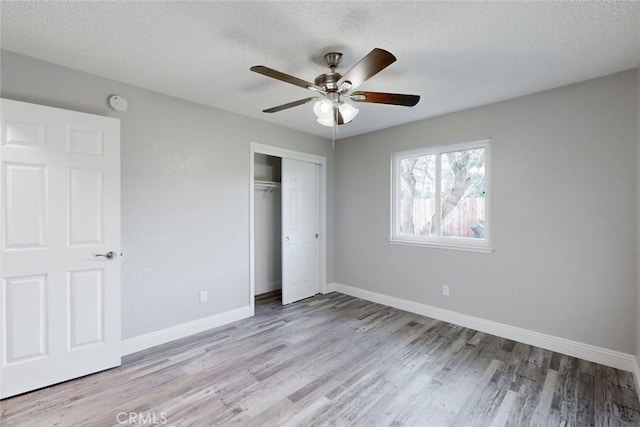 unfurnished bedroom with ceiling fan, a textured ceiling, a closet, and light hardwood / wood-style flooring