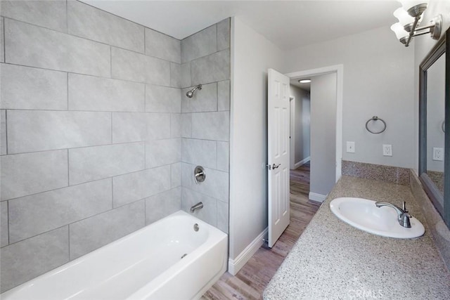 bathroom with tiled shower / bath, wood-type flooring, and vanity