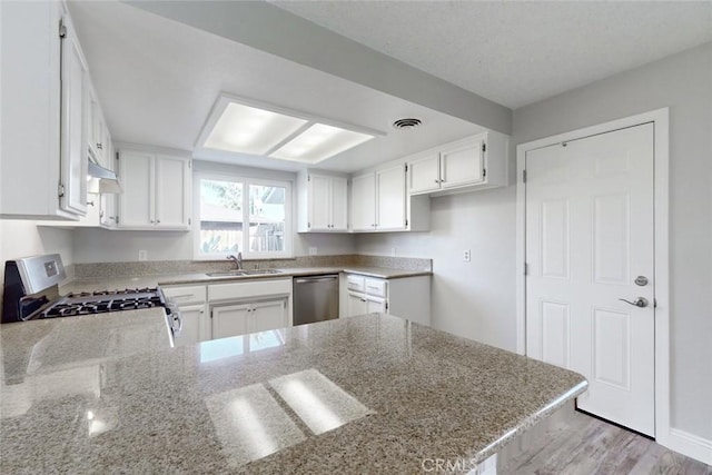 kitchen featuring stainless steel appliances, light stone countertops, white cabinets, and kitchen peninsula