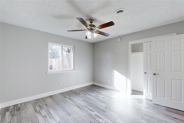 unfurnished bedroom with ceiling fan, light hardwood / wood-style flooring, a closet, and a textured ceiling