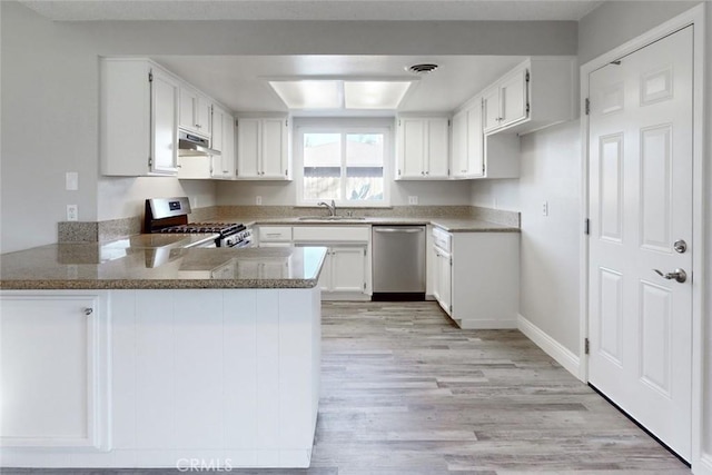 kitchen featuring sink, white cabinetry, stainless steel appliances, light hardwood / wood-style floors, and kitchen peninsula