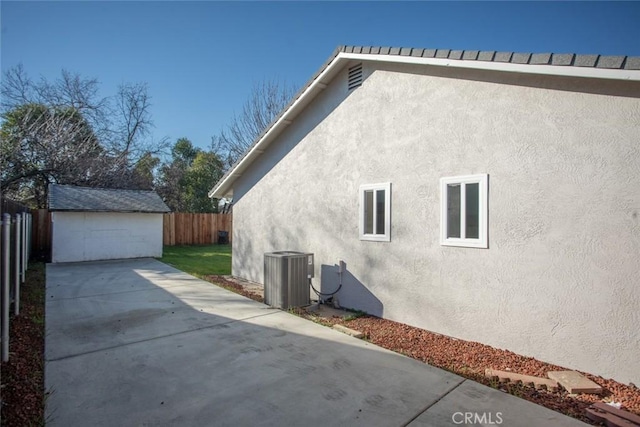 view of property exterior with central AC, a patio area, and an outbuilding