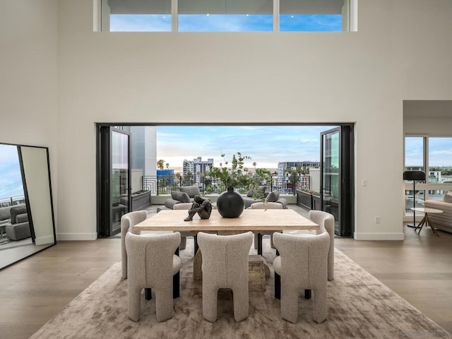 dining space with a towering ceiling and light hardwood / wood-style flooring