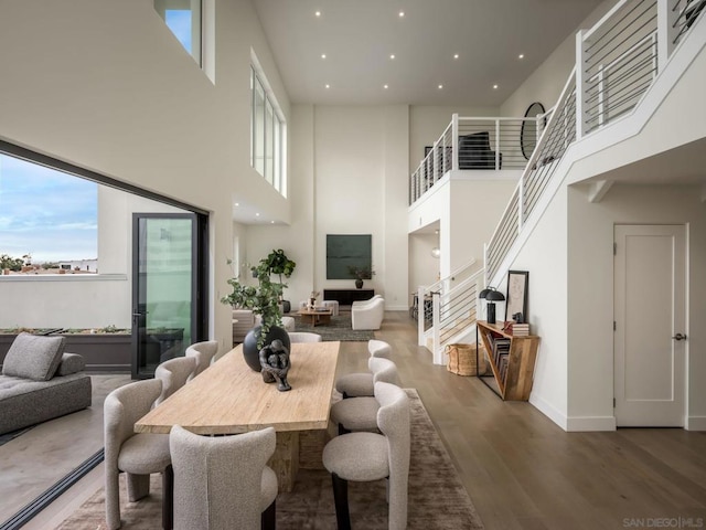 dining space with dark wood-type flooring, a healthy amount of sunlight, and a high ceiling