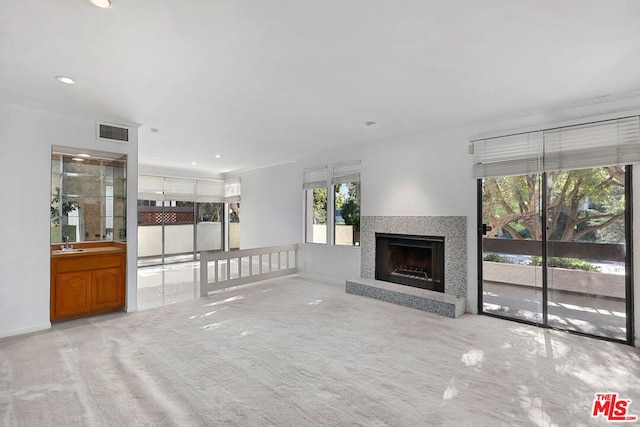 unfurnished living room with crown molding, sink, and light carpet